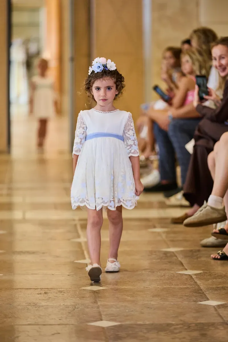 A young student walking the catwalk at a fashion show.