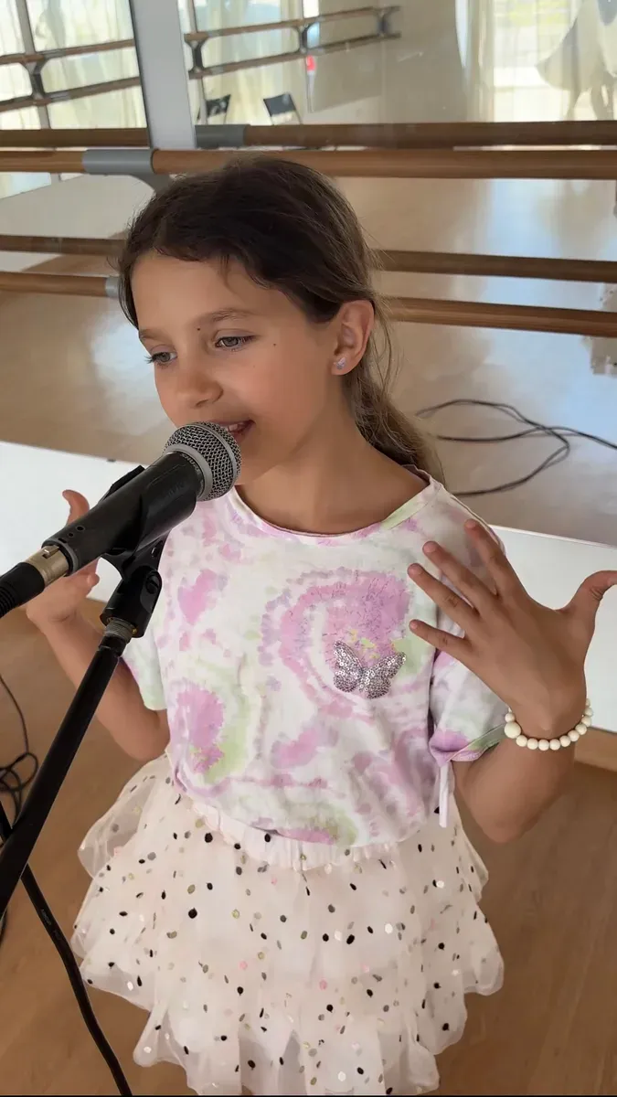 A young student expressing herself confidently at the microphone.