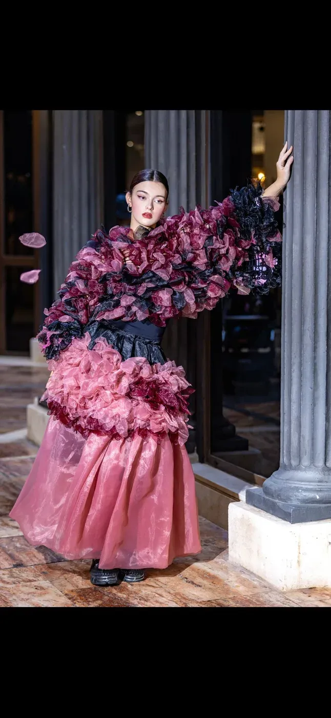 Editorial photoshoot of a young model in a pink ruffled couture dress.